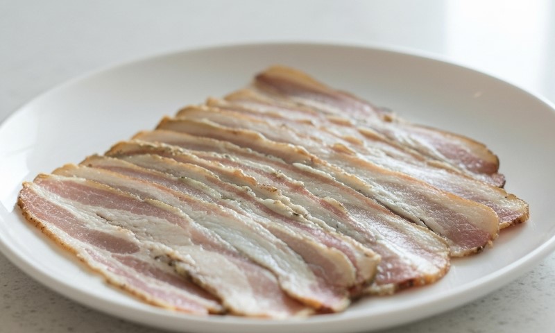 Sliced expired bacon arranged on a white plate