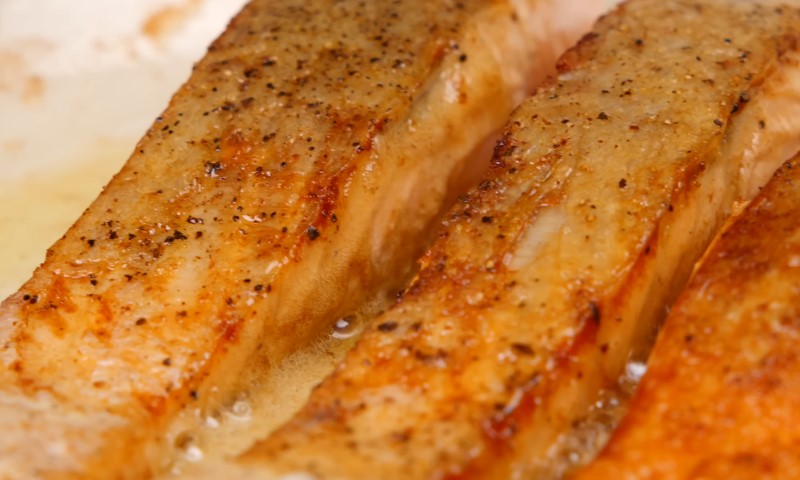 Two fish fillets are being cooked in a pan
