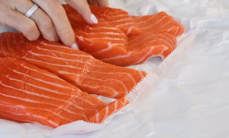 A person is cutting salmon on a piece of paper