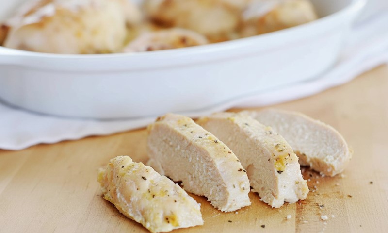 Sliced chicken breast arranged neatly on a wooden cutting board