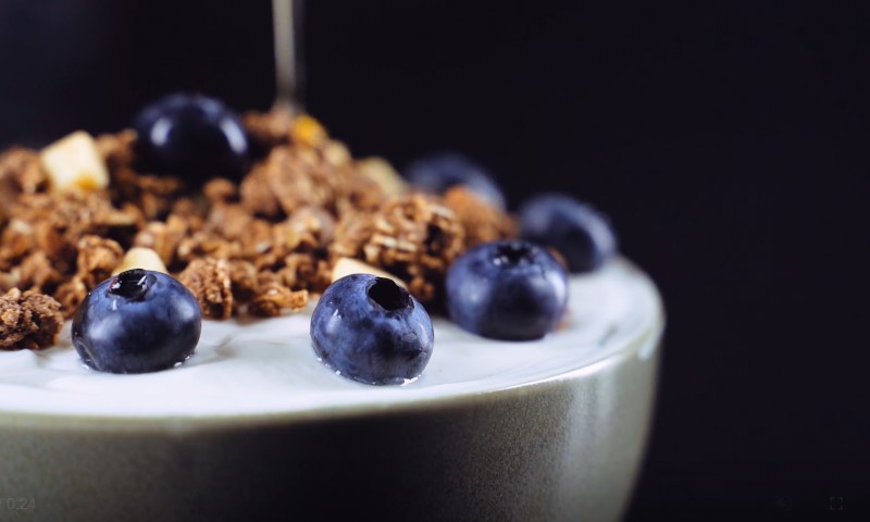 A bowl of creamy yogurt topped with granola and plump blueberries